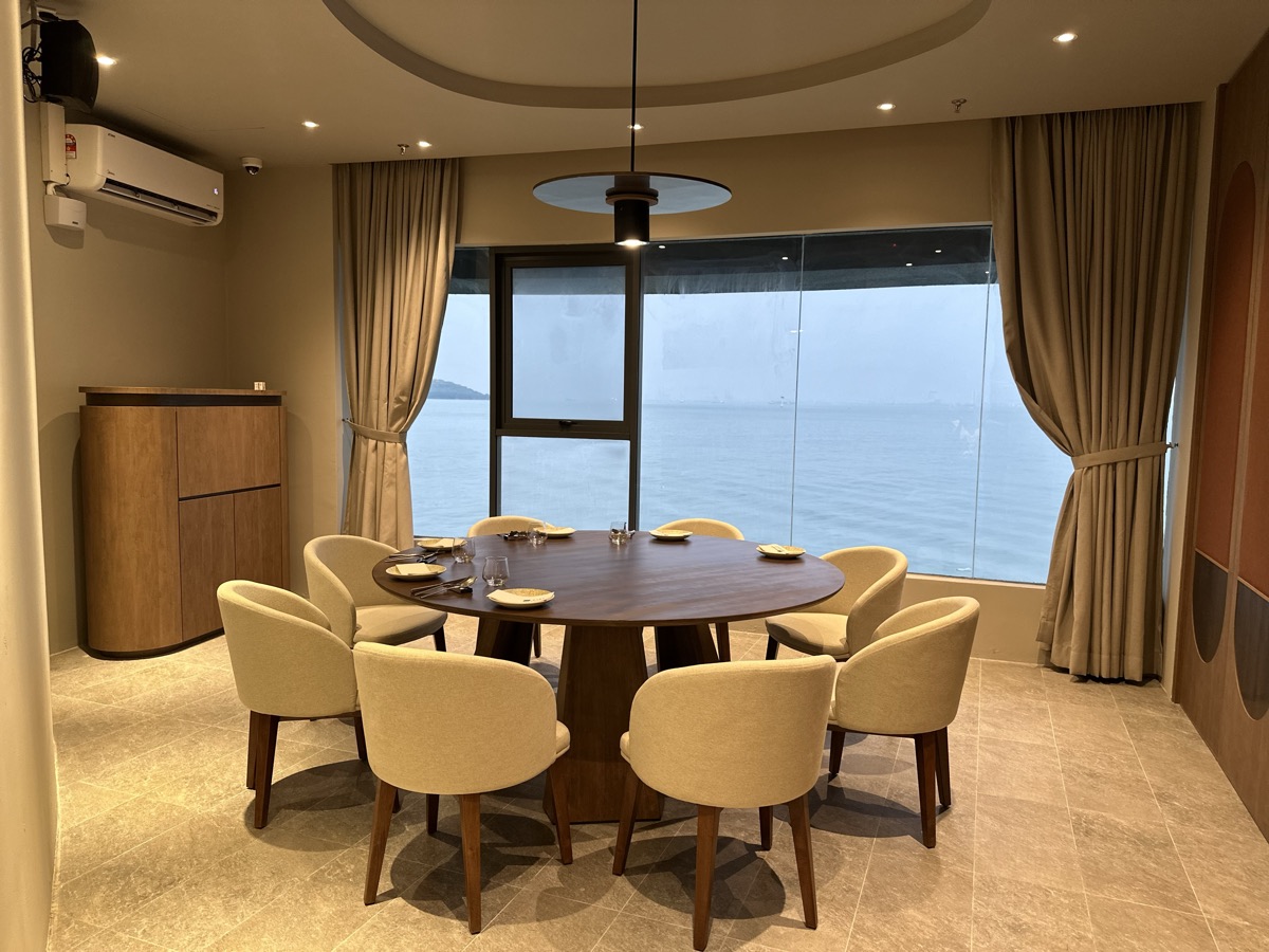 A round table with cream armchairs in front of a sea-view window