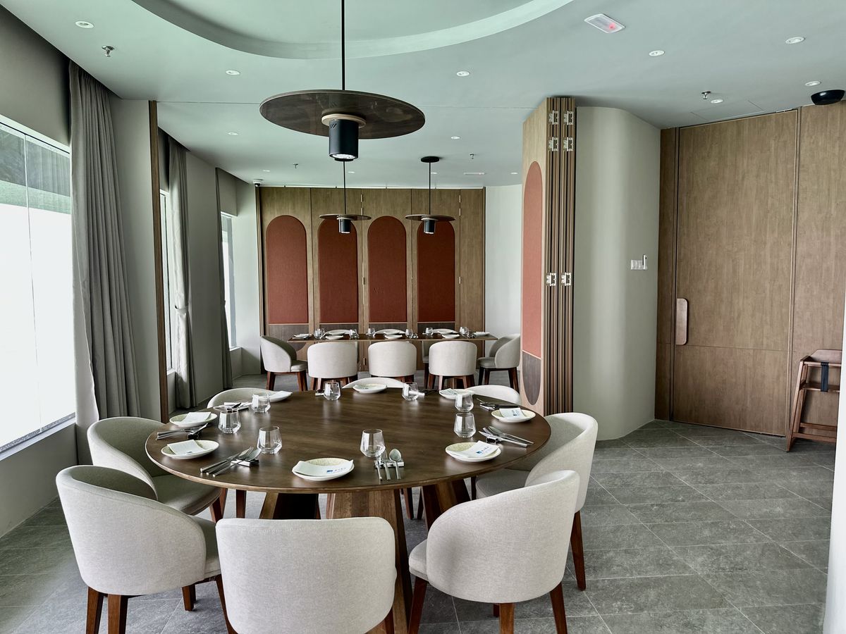 A round table in a private room with a second table set behind it, beneath terracotta arched panels